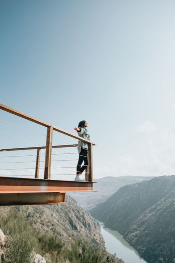 Low angle view of woman standing by railing against sky