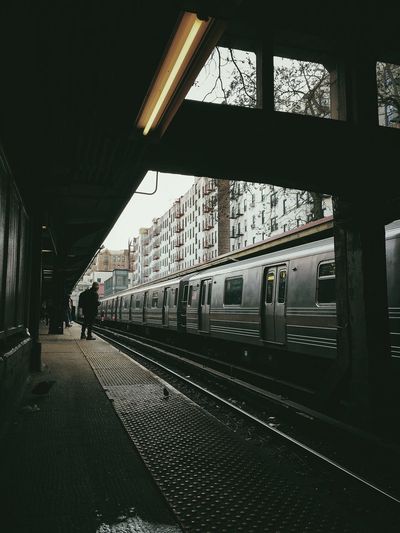 Train at railroad station in city against sky