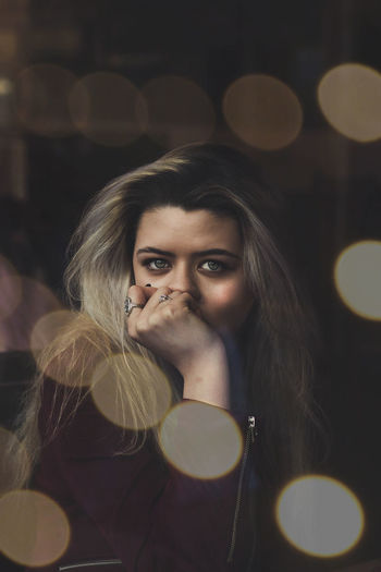 Portrait of beautiful young woman amidst defocused lights