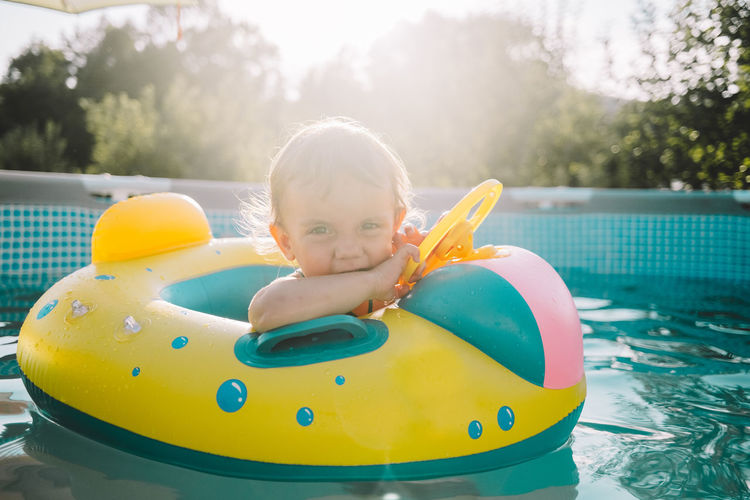 Portrait of cute baby boy sitting in inflatable ring on swimming pool