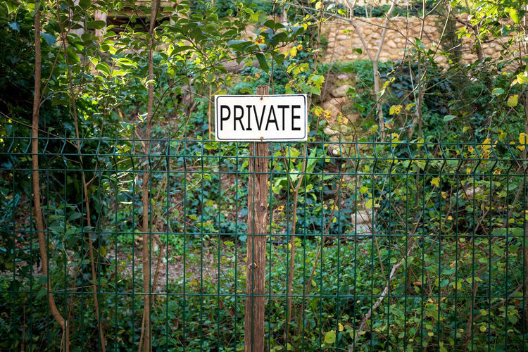 View of signboard on fence against plants