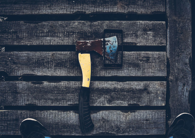 High angle view of broken mobile phone along with axe on wooden platform