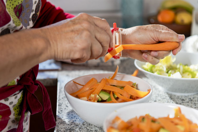 Close up of old lady hands making a salad.