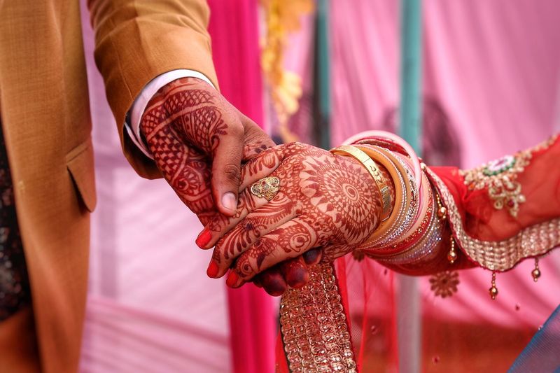 Cropped image of couple holding hands at wedding ceremony