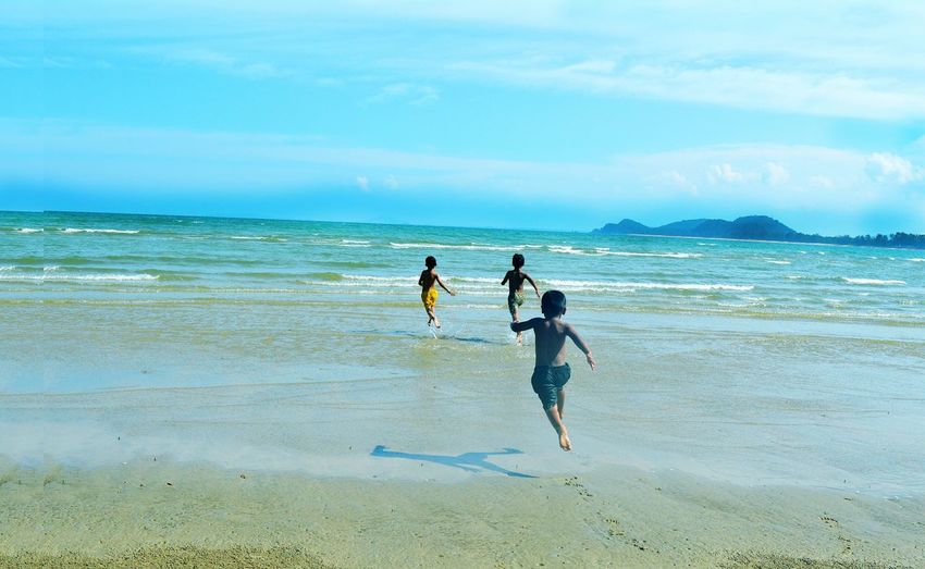 People running on beach against sky
