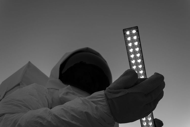 Low angle view of a scientist holding illuminated light against sky