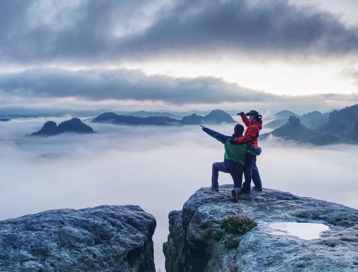 Romantic date in misty mountains. man shows girlfriend something interesting in far distance.