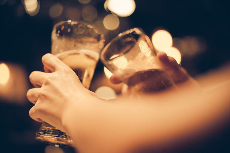 Cropped hands of people toasting beer glasses in bar