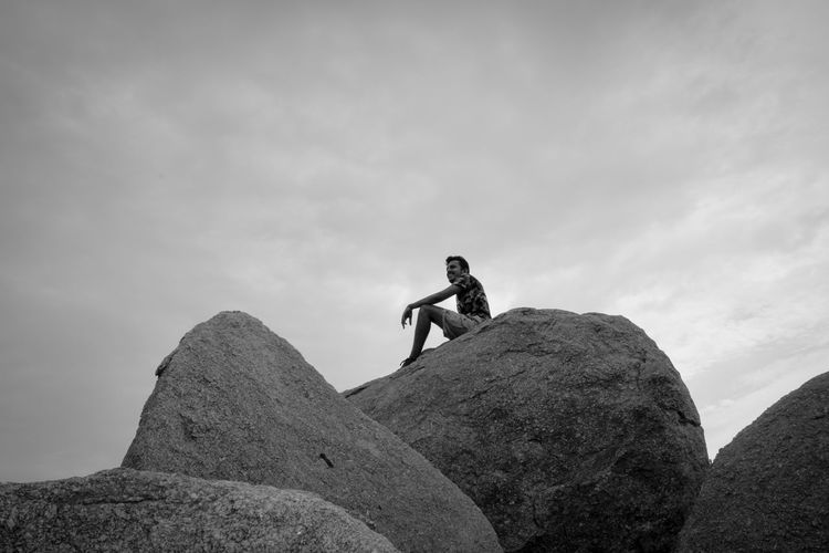 Low angle view of man on rock against sky