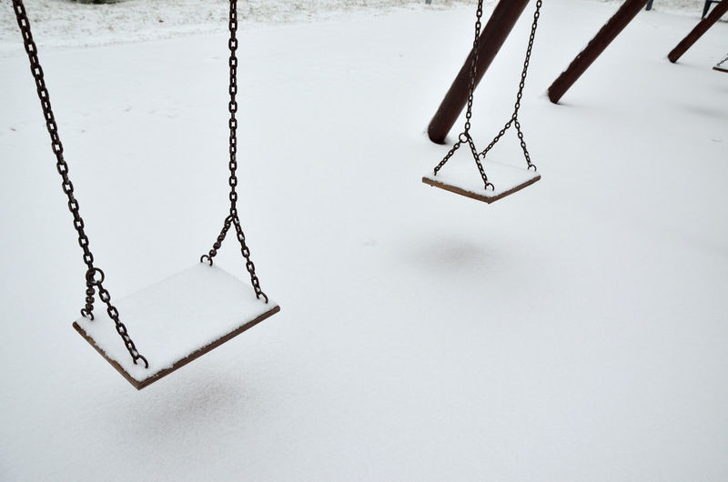Two swings in city park covered with snow