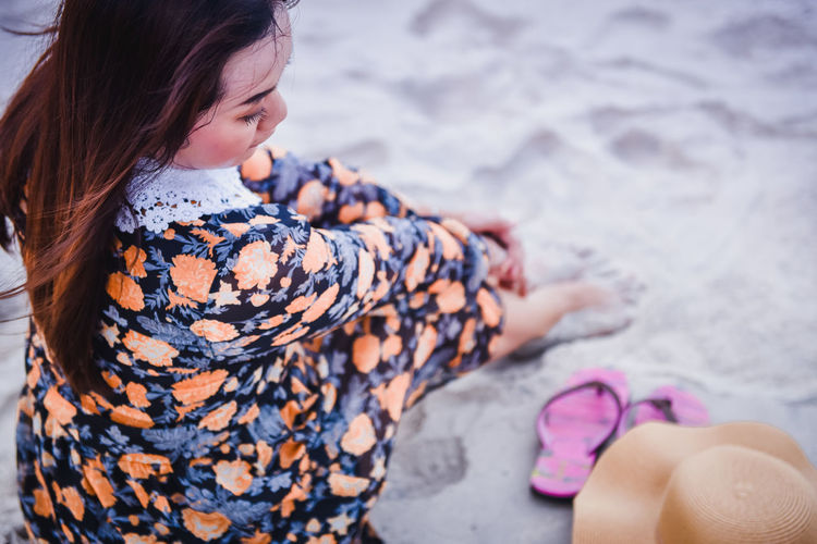 High angle view of woman sitting on sand at beach