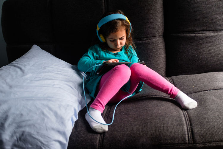Young girl playing ipad game on a couch