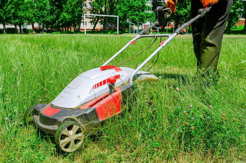 Electric hand lawn mower at stadium. lawn care on sports field.