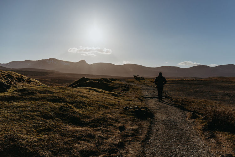 Silhouette man walking on mountain against sky