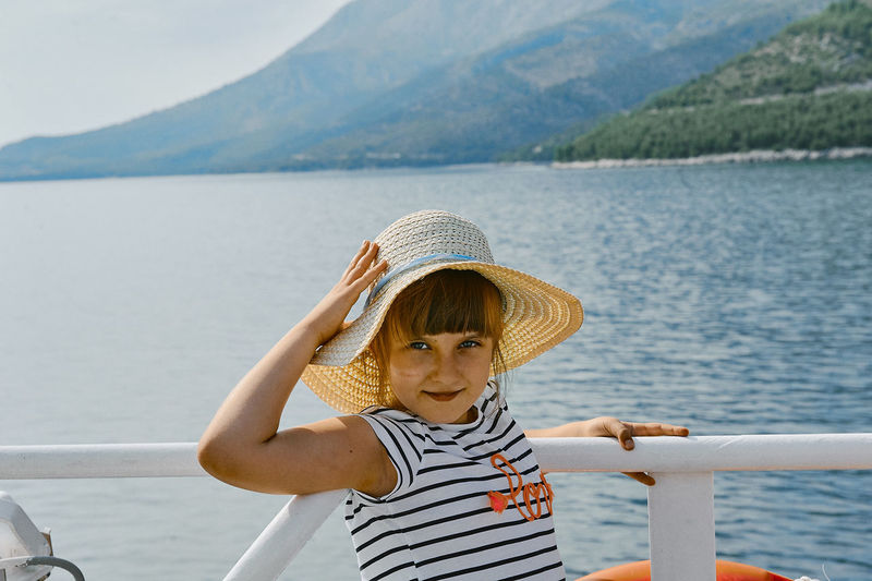Portrait of girl wearing sun hat in boat on sea