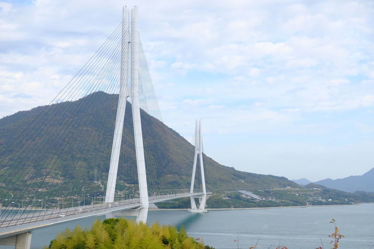 Suspension bridge over river against sky