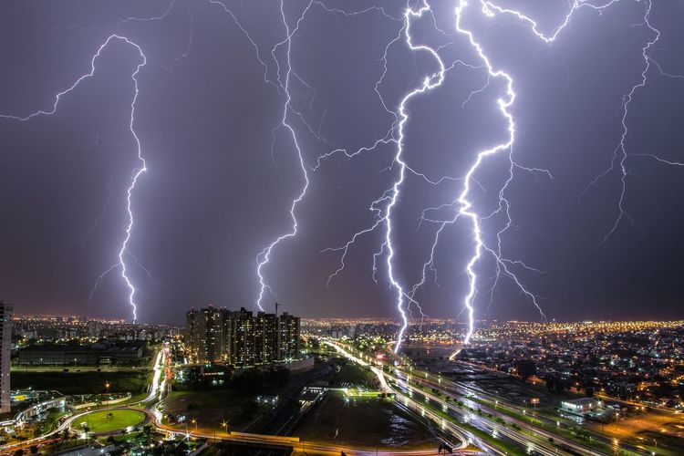 Lightning over illuminated city buildings at night
