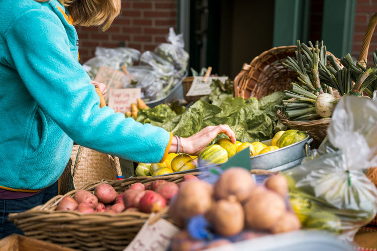 Young woman looking at vegetables at farmers market