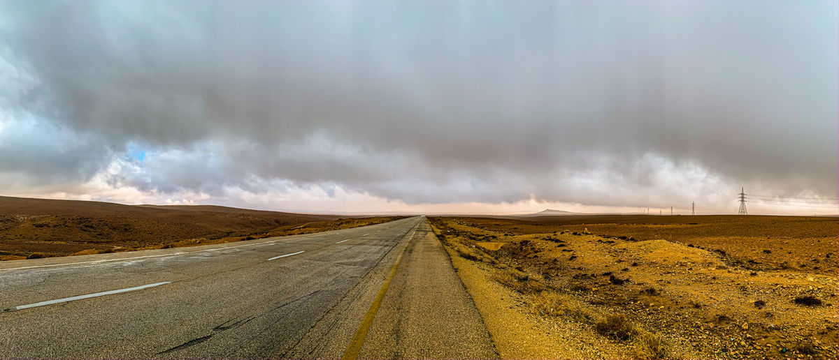 Road passing through desert against sky