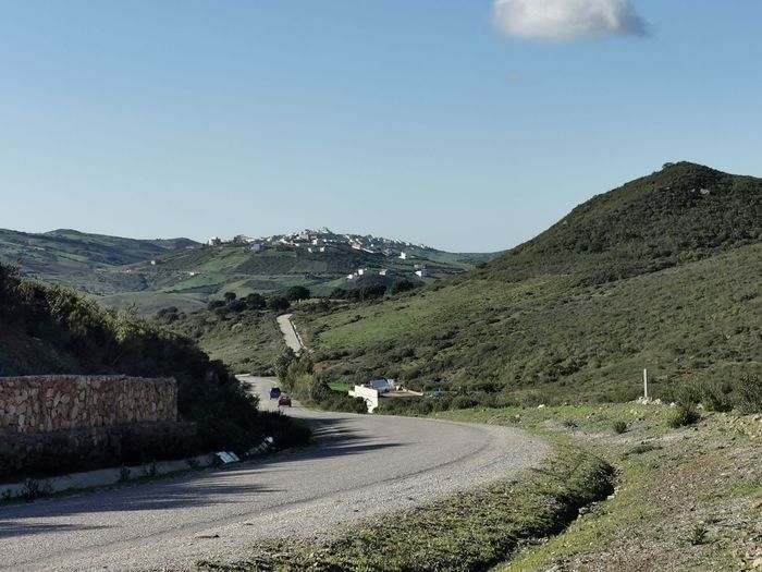 Road leading towards mountains against clear sky