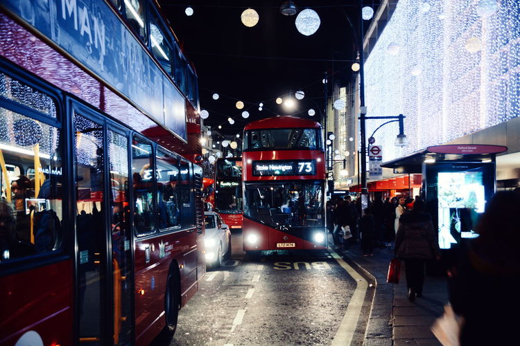 Illuminated double-decker busses on city street at night