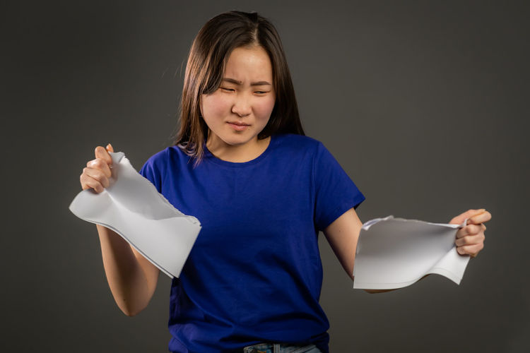 Girl holding paper while standing against black background