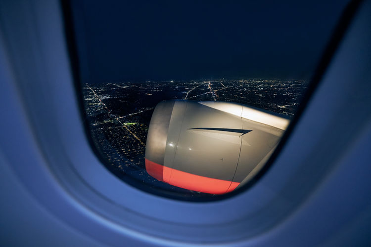 View from window of airplane during take off against illuminated city at night.