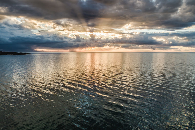 Scenic view of seascape against cloudy sky at sunset