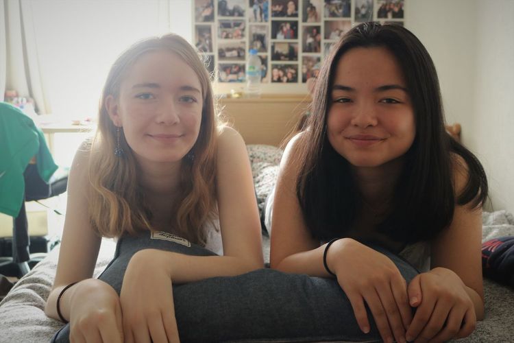 Portrait of smiling friends lying on bed at home