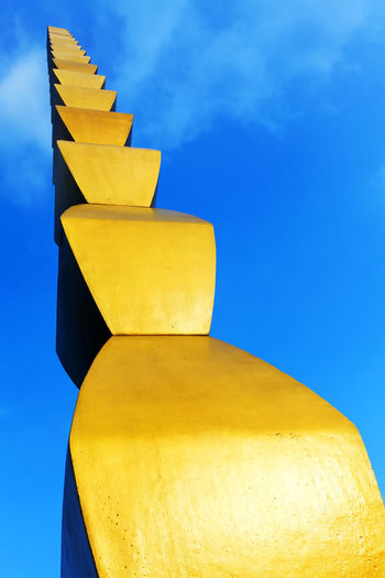 Low angle view of the endless column sculpture against blue sky