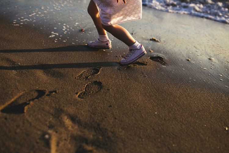 Low section of girl walking at beach