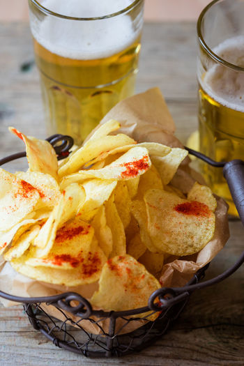 High angle view of fresh crunchy potato chips with beer on table