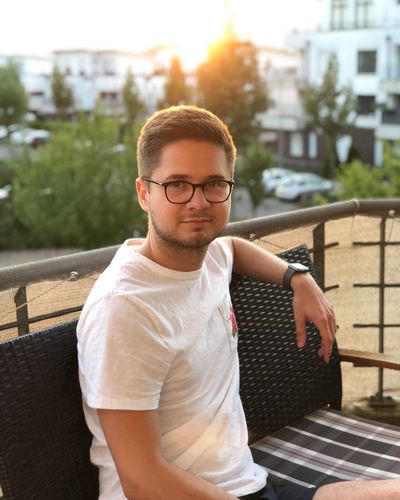 Portrait of young man sitting in city during sunset