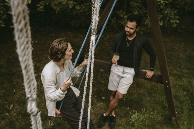 High angle view of smiling men with drinks enjoying in backyard