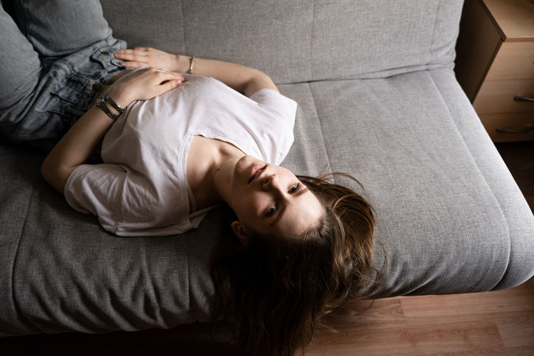 High angle portrait of woman lying on sofa at home
