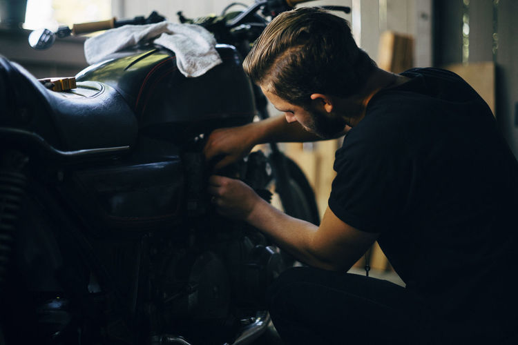 Man repairing motorcycle in garage