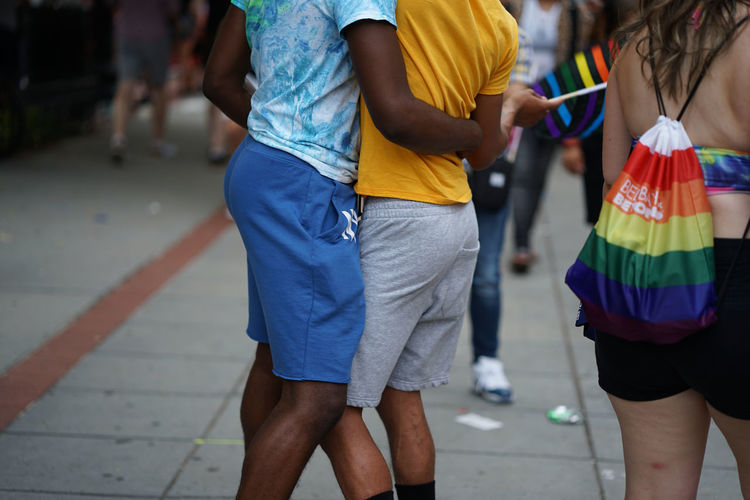 Low section of people kissing on street during gay pride 
