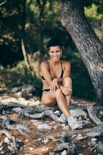 Portrait of young woman wearing bikini while sitting on field