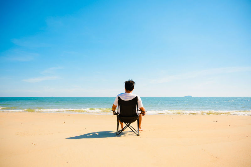 Rear view of man sitting on beach