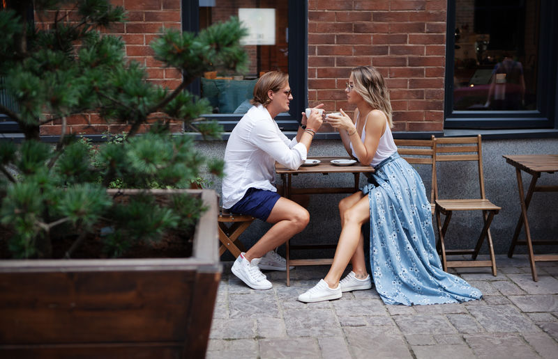 Young trendy couple talking at coffee shop on date. loving couple having cup of coffee at street 