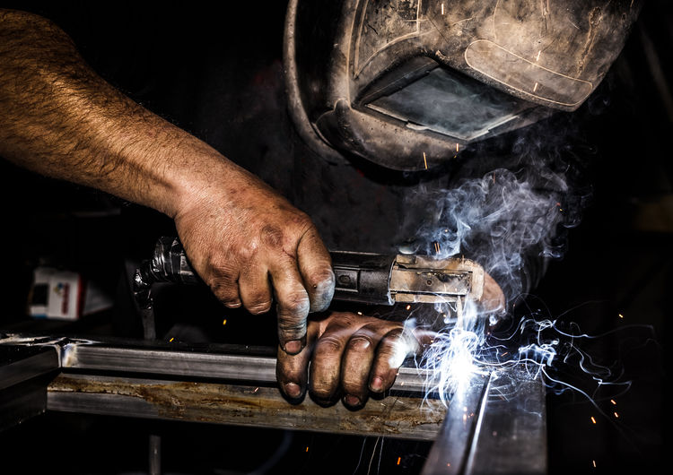 Close-up of male welder welding metal in factory