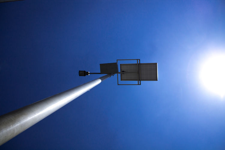 Low angle view of illuminated lamp against clear blue sky