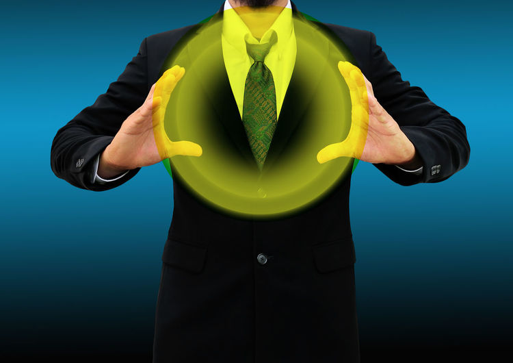 Digitally generated image of businessman holding yellow circle while standing against blue background