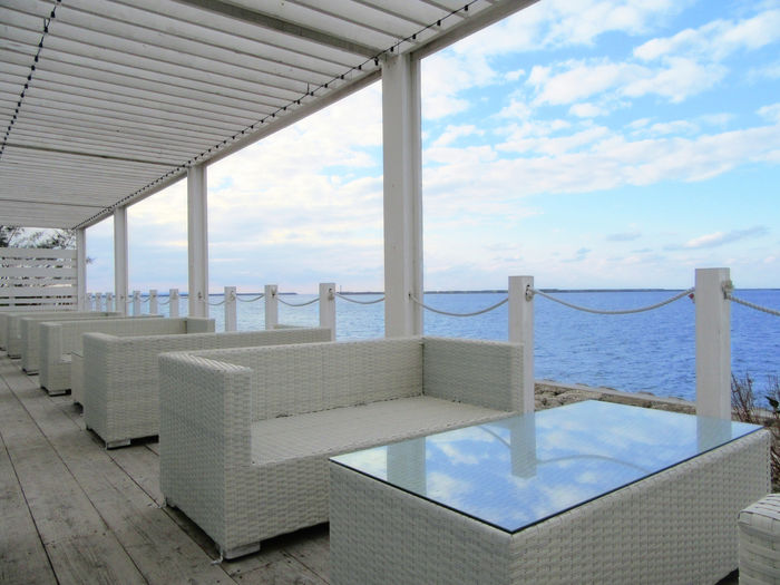 White couch and table on the deck by the sea.