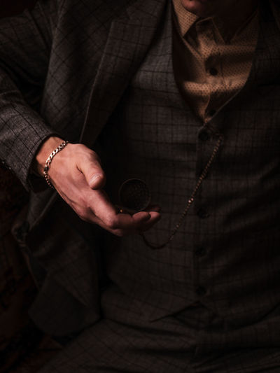 Midsection of person holding pocket watch at home