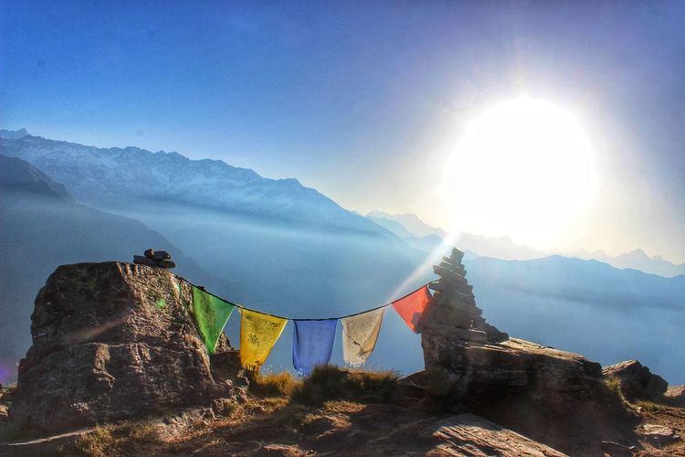 Prayer flags on mountains against bright sun