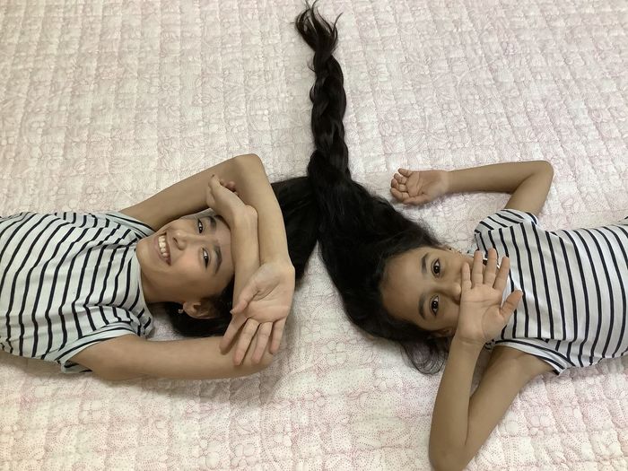 High angle portrait of girls relaxing on bed at home