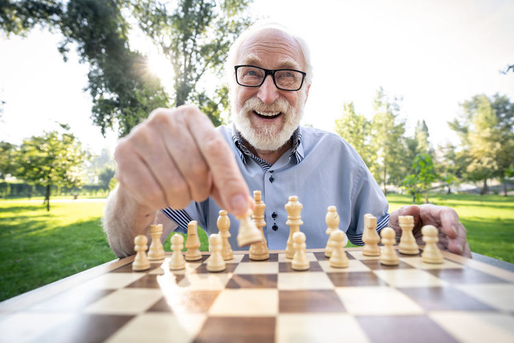 Portrait of man playing with chess against background