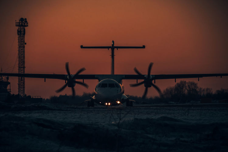 Low angle view of airplane against sky during sunset