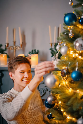 Portrait of smiling young man holding christmas tree
